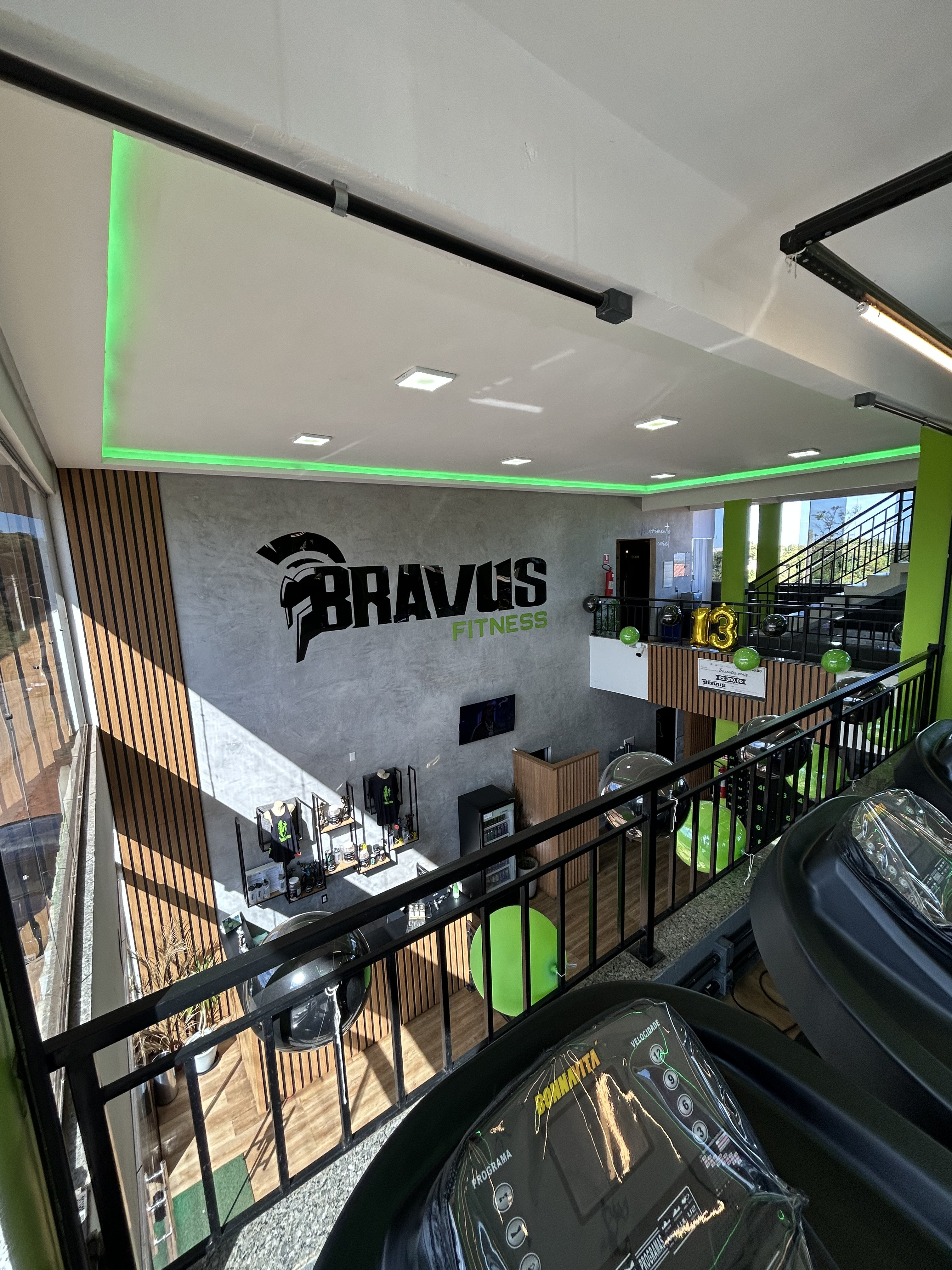 Vista do mezanino para a recepção e loja da Academia Bravus Fitness