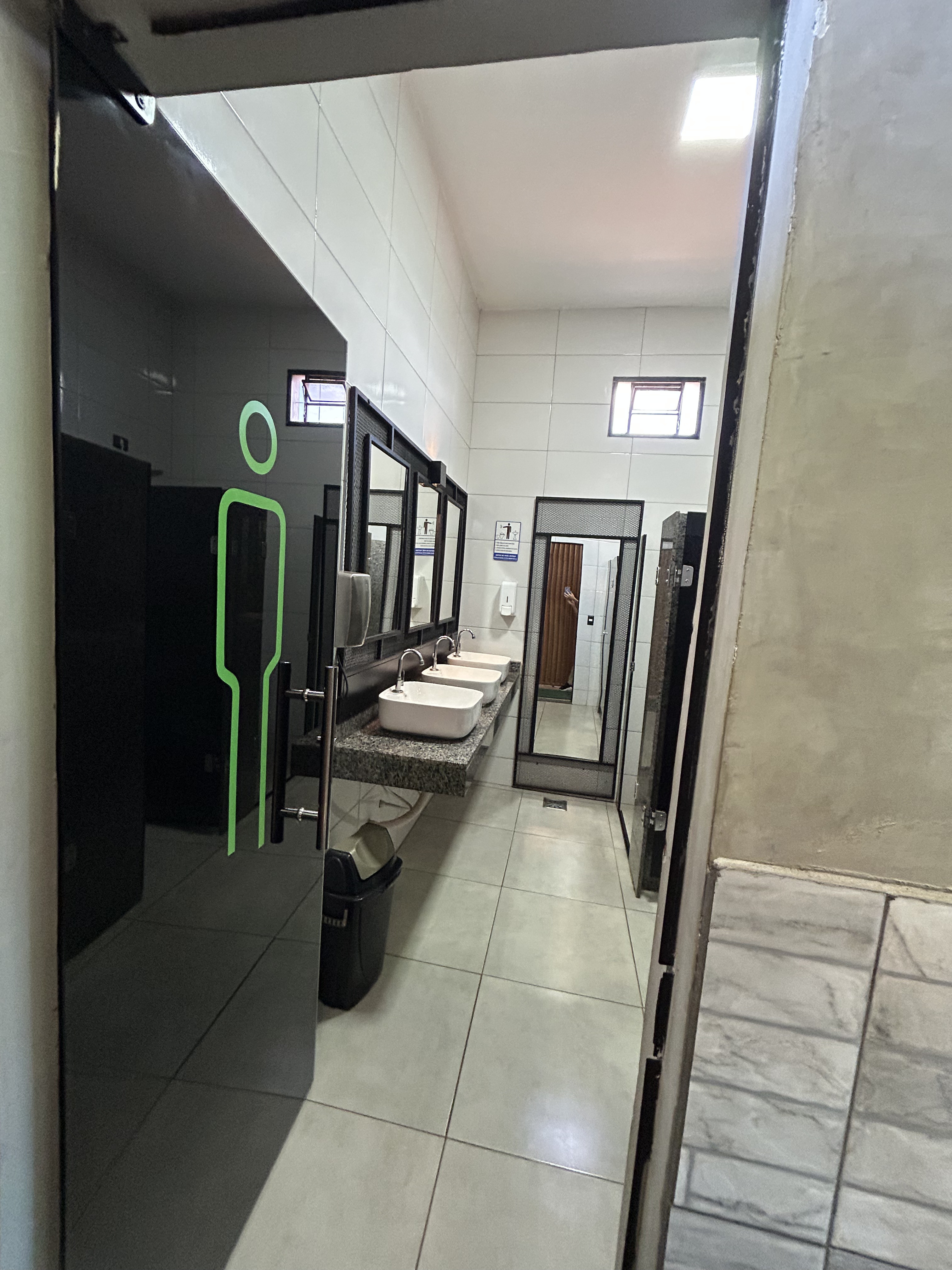 Vestiário masculino da Academia Bravus Fitness, com pias e boxes de chuveiro